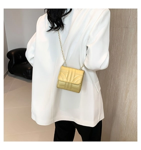 Detail of metallic gold crossbody bag with geometric embossing and chain strap