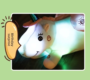 Close-up detail of a colorful glowing unicorn plush toy illuminating in a dark setting