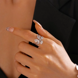 Close-up of silver metal hollow flower ring with radial texture on a model's hand