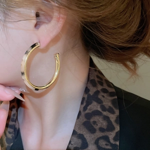 Close-up of vintage C-shape leopard print hoop earrings worn on a model's ear