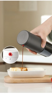 Close-up of glass oil dispenser with precision red spout and leak-proof return hole