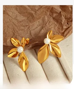 Detailed close-up of 18K gold-plated flower earrings with natural pearls on fabric