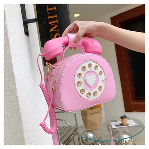 Macro detail of pink retro telephone shaped crossbody bag with glossy patent finish