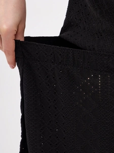 Detailed view of black eyelet embroidery fabric and discreet side pocket on pajamas