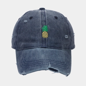 Detail of distressed washed denim baseball cap with yellow pineapple embroidery