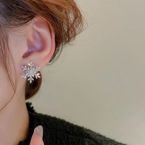 Close-up of snowflake stud earring with pavé zircon stones on a model's ear