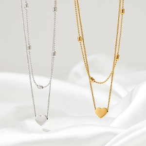 Close-up of double-layer heart anklets in gold and silver on white silk fabric