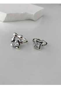 Detail of silver square cutout rings with clear gemstones on white minimalist background