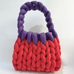Detailed knit texture of a handmade chunky yarn handbag in red and purple color block