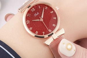 Dettaglio del quadrante rosso con numeri arabi e anse a fiocco su orologio in maglia