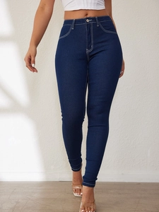 Detailed close-up of dark blue slim fit jeans with stylish white contrast stitching