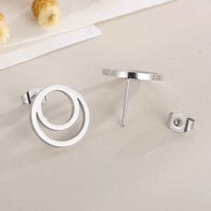 Close-up of silver double-circle stud earrings with cubic zirconia on beige background
