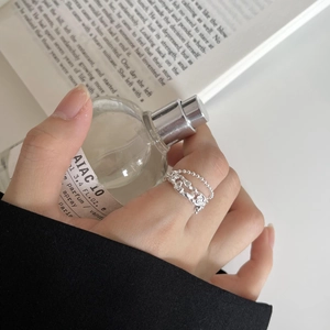 Close-up of stacked 925 sterling silver rings featuring a beaded chain and wavy texture