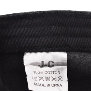 Detail shot of the 100% cotton wash care label and J-C brand tag inside the black cap