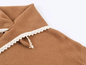 Détail du col d'un haut en maille camel avec une bordure en dentelle blanche raffinée