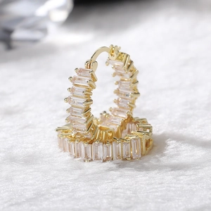 Close-up of gold hoop earrings with baguette cut AAA cubic zirconia stones on faux fur