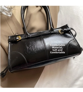 Close-up of black glossy leather handbag with gold metal buckles on a trench coat