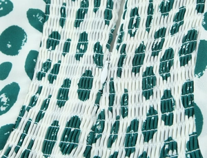 Macro detail of green leopard print smocking fabric with a white invisible zipper