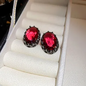 Vintage oval ruby earrings with retro black metal setting on white textured background