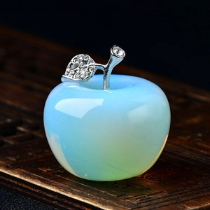 Macro detail of a light blue crystal apple with silver rhinestone leaves on dark wood