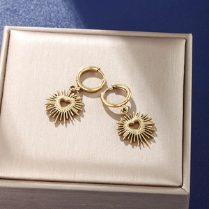 Boucles d'oreilles créoles cœur soleil doré posées sur un écrin en velours luxueux