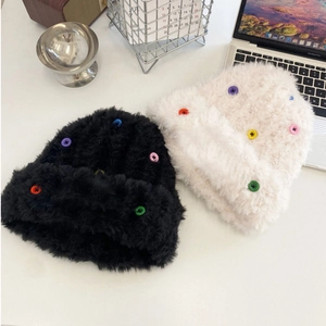 Close-up of thick plush knit beanies in black and white with colorful button accents