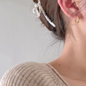 Close-up of elegant gold striped hoop earring and clear acrylic hair clip on model
