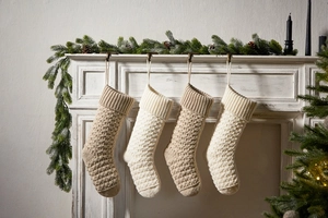 Knitted Christmas stockings in cream and beige hanging on a white vintage fireplace
