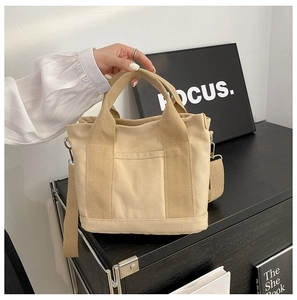 Detail of beige canvas tote bag with front pocket and adjustable shoulder strap