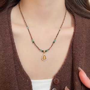Detail of tiger eye bead necklace with a gold-plated gourd pendant and zircon inlay