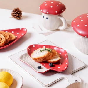 Close-up of red polka dot mushroom ceramic dinnerware set including plate and lidded cup