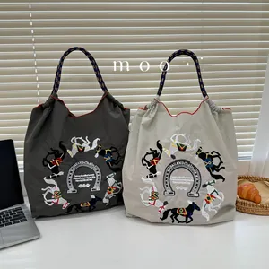 Detail of grey and beige nylon tote bags featuring intricate horse embroidery and woven handles