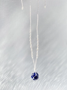 Détail d'un collier en cordon blanc tissé à la main avec pendentif en pierre lapis-lazuli