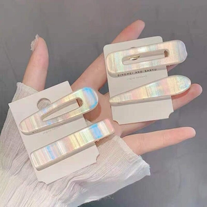 Detailed view of four colorful iridescent geometric hair clips on a white display card