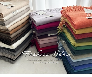 Detailed view of stacked colorful cashmere feel scarves with soft tassel fringe edges