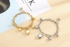 Détail de bracelets cœur dorés et argentés avec chaînes à billes sur magazine de mode