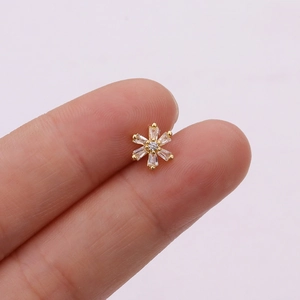 Macro view of a small rose gold snowflake earring with clear baguette zircon stones