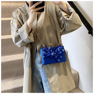 Blue satin evening bag with rhinestone gems and chain strap worn by a model