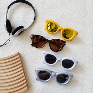 Retro thick frame round sunglasses in yellow, white, and blue colors on a textured surface