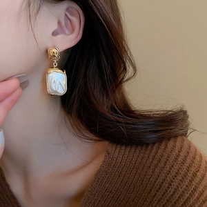 Close-up of vintage baroque pearl square earrings with hammered gold metal details