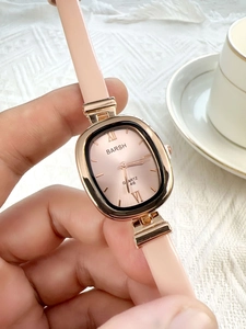 Close-up of elegant pink leather strap quartz watch with oval rose gold case held by hand
