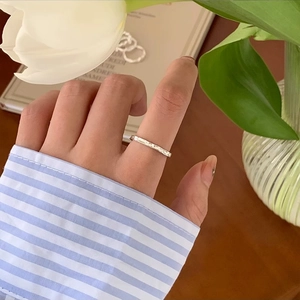 Detail of silver textured ring worn on finger with a white tulip and lifestyle background