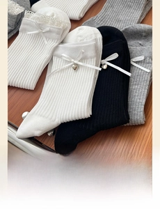 Detail of ribbed cotton mid-tube socks with elegant silk bows and heart-shaped charms