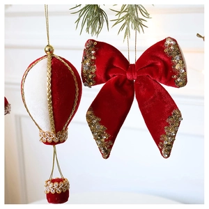 Close-up of velvet hot air balloon and red sequin bow hanging on Christmas pine branches