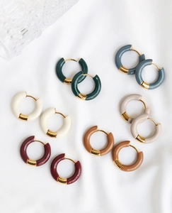 Boucles d'oreilles créoles en émail et plaqué or 18K sur un tissu blanc texturé élégant