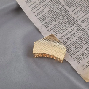 Close-up of a golden geometric metal hair claw clip placed on a vintage book