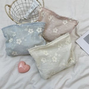 Detailed embroidery view of floral lace makeup bags in blue, pink, and beige