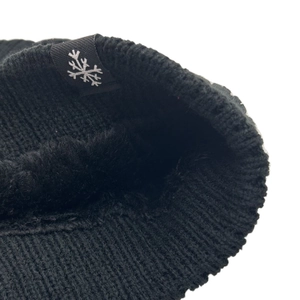 Detail of warm black knit beanie featuring thick faux fleece lining and snowflake tag