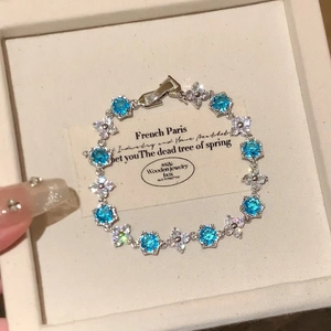 Elegant silver bracelet with blue zircon stones and clover patterns on jewelry box