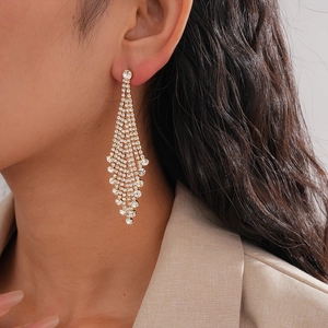 Close-up of sparkling diamond tassel drop earrings worn by a model in golden finish
